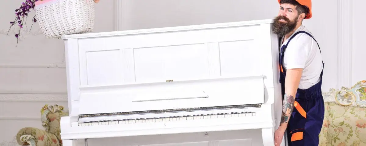 Ein Möbelpacker versucht ein Klavier anzuheben