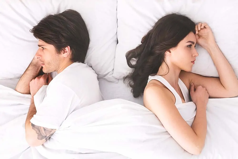 Ein Bild von einem Paar das im Bett liegt und sich gestritten haben könnte.