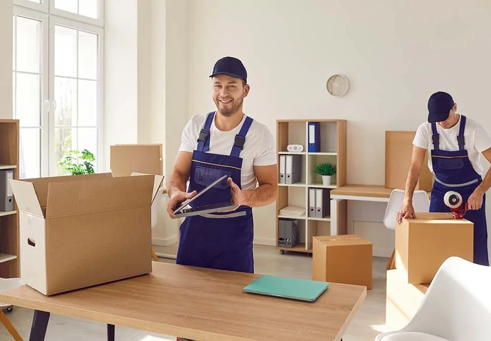 Zwei Mitarbeiter eines Umzugsunternehmens bereiten Kisten für den Transport von einem Büro zum anderen vor.