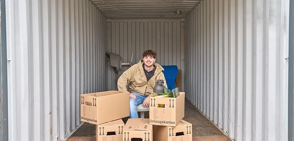 Junger Mann lagert Gegenstände in Lagercontainer ein