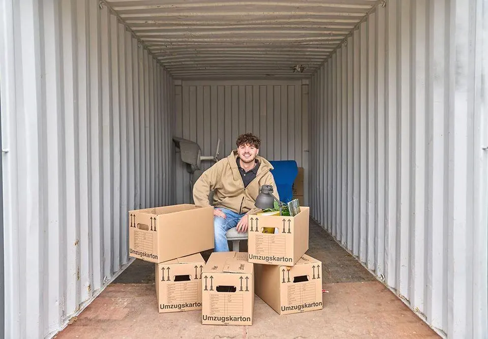 Junger Mann lagert Gegenstände in Lagercontainer ein