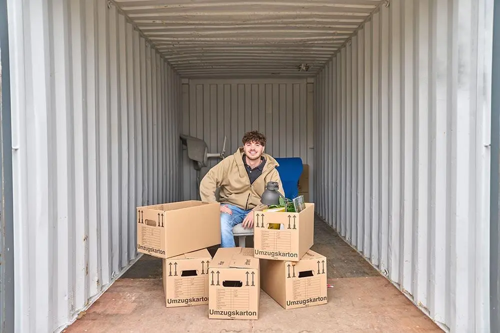 Junger Mann lagert Gegenstände in Lagercontainer ein
