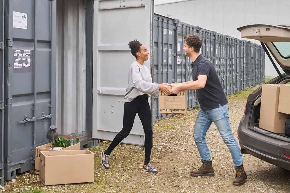 Frau und Mann räumen Kisten in Lagercontainer ein