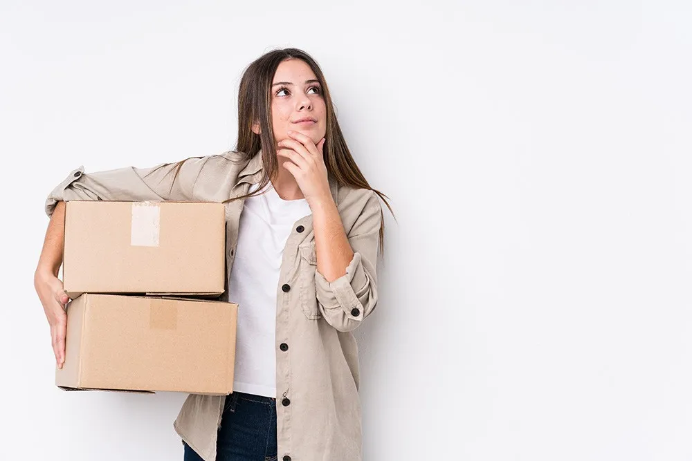Frau mit Kartons überlegt, wo sie einlagern soll